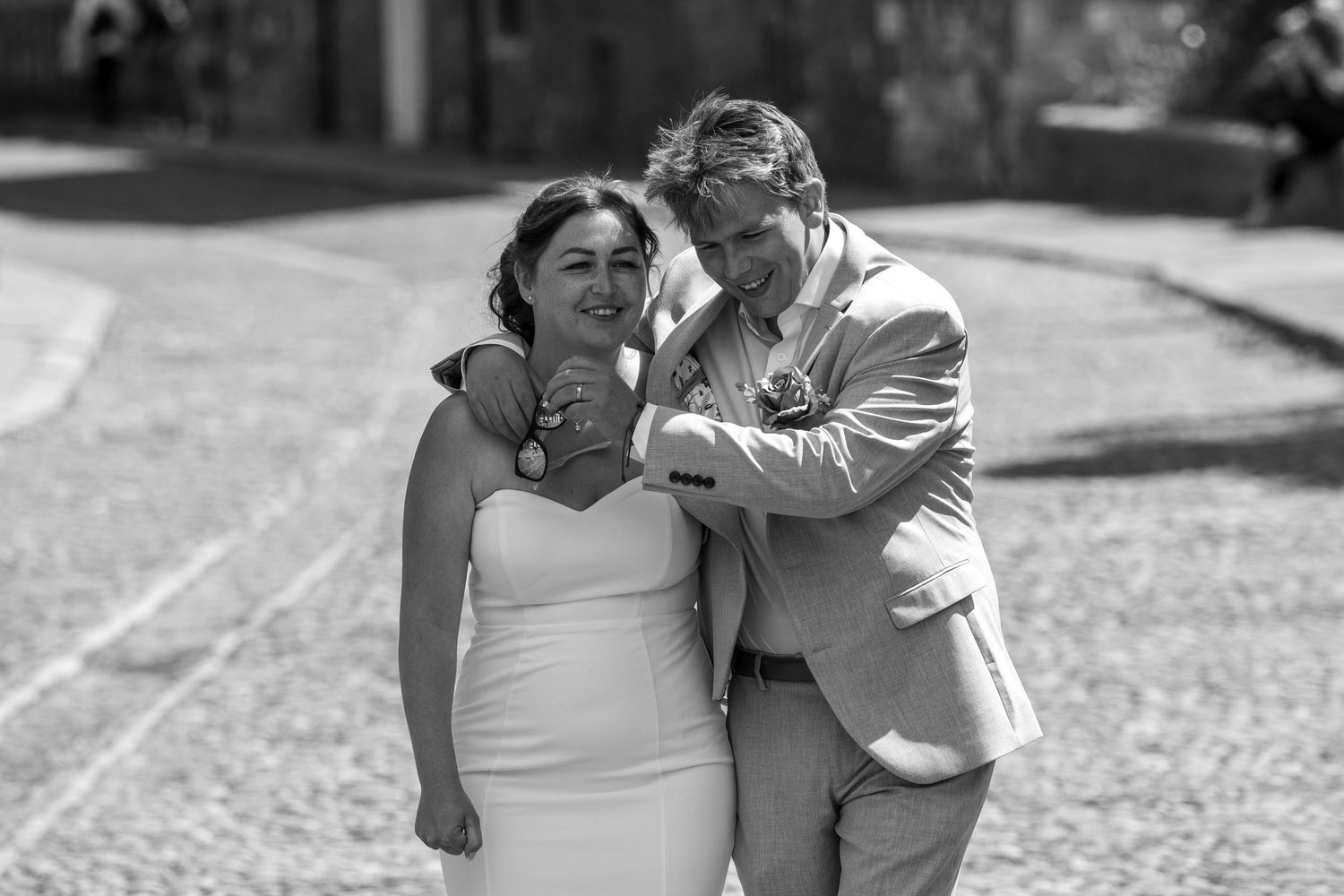 Black and white wedding photo of a couple laughing together outdoors.