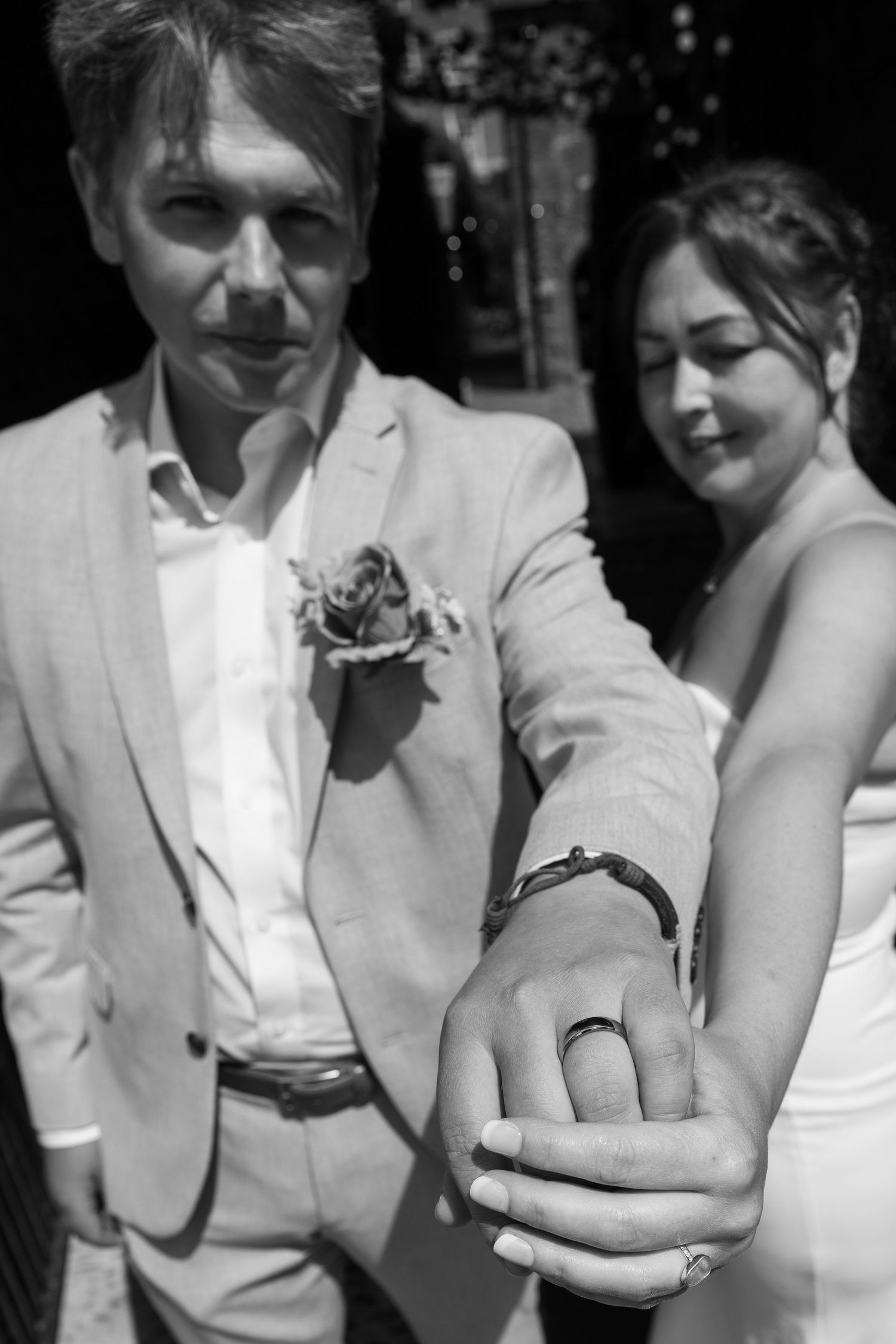 Black and white photo showing wedding rings and formal attire.