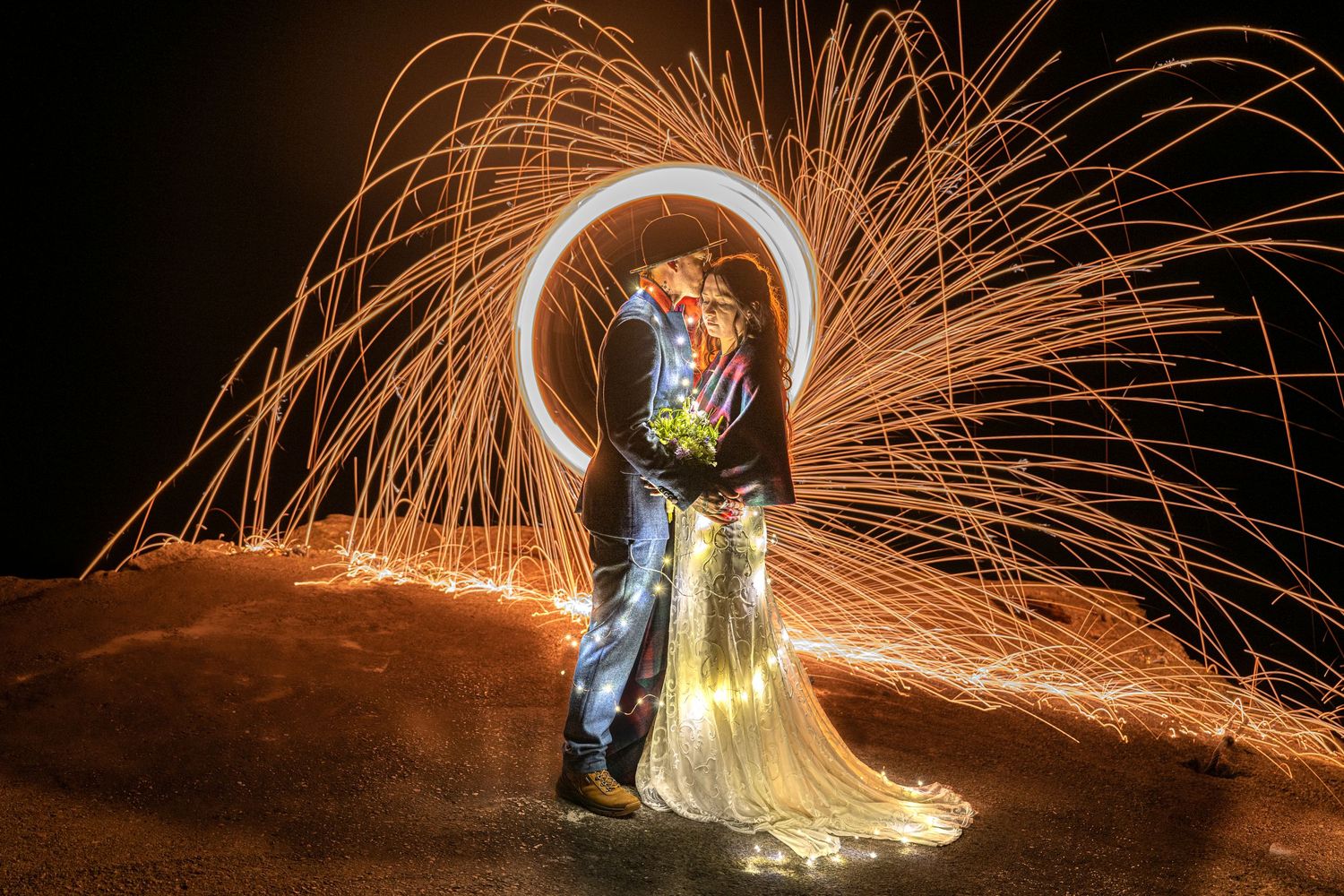 Steel wool photography creates spectacular light trails around wedding couple at night.