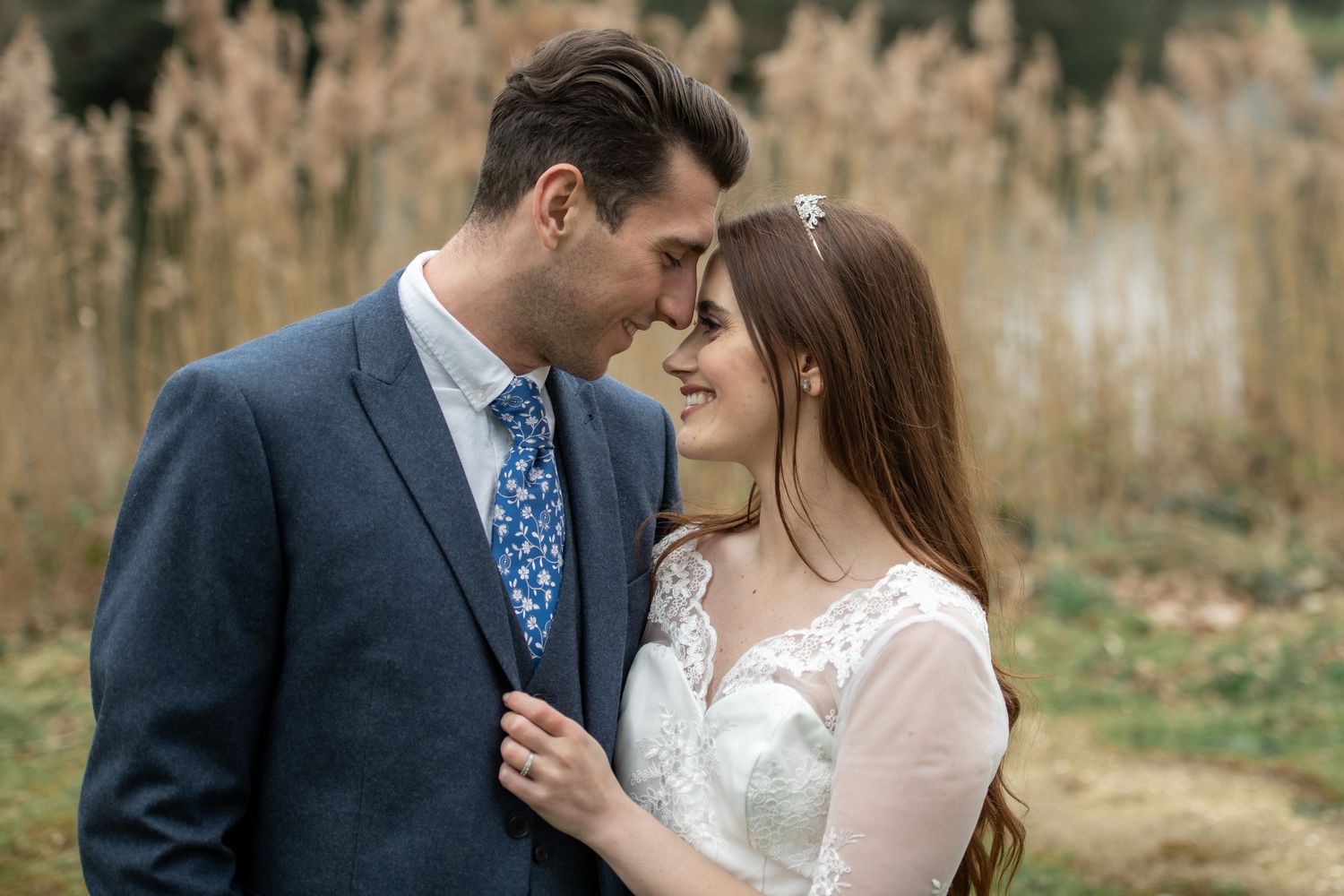 Intimate moment between couple against natural backdrop of tall grass.