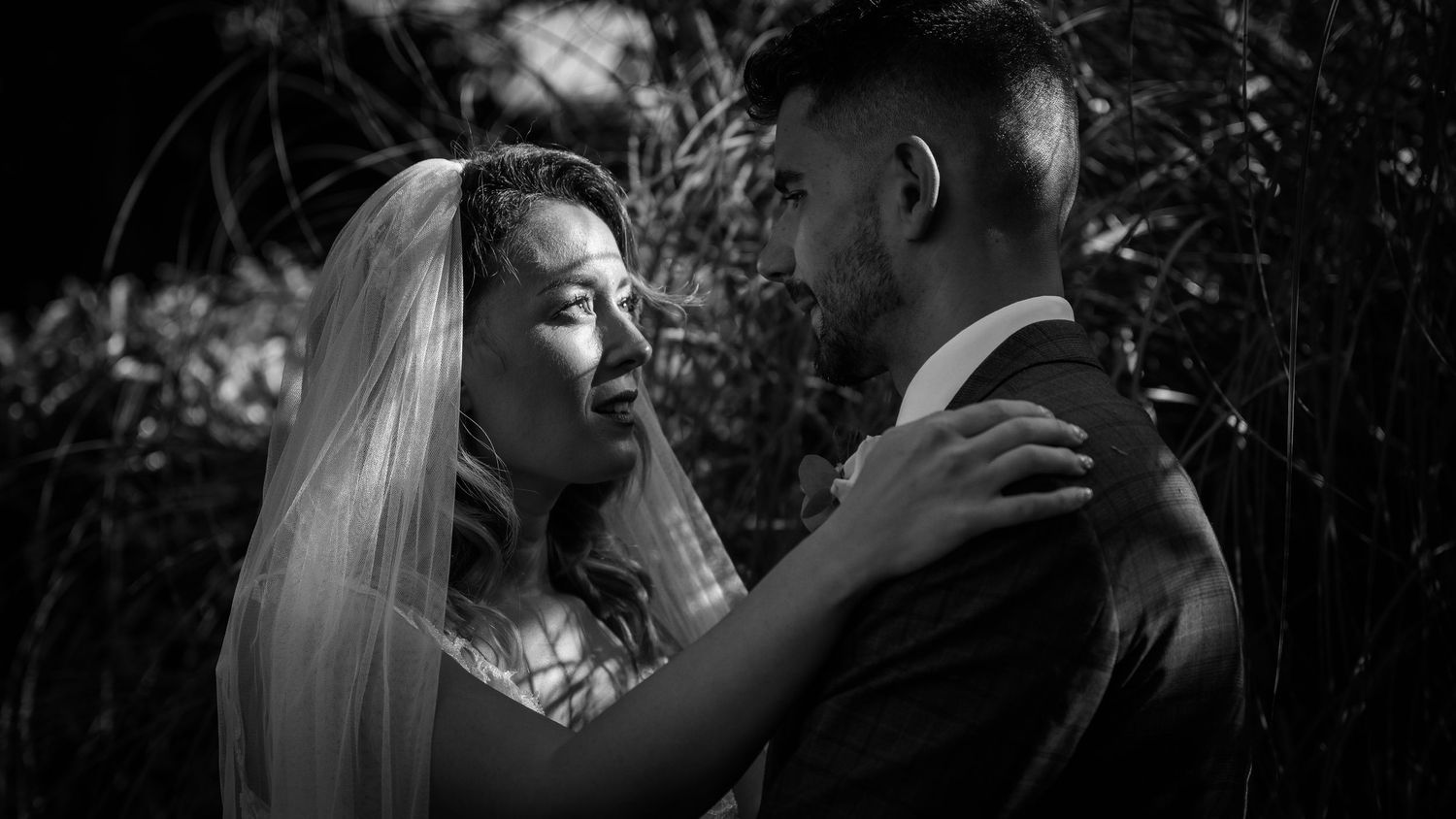 Black and white portrait of newlyweds embracing outdoors.
