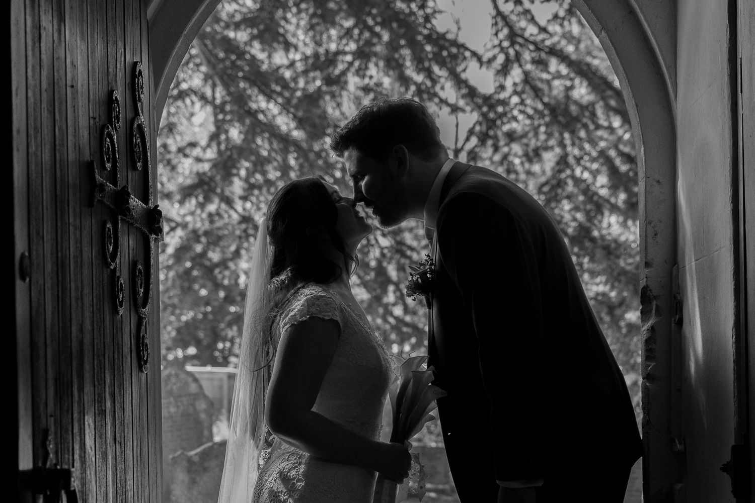 Romantic silhouette of couple in church doorway on wedding day.