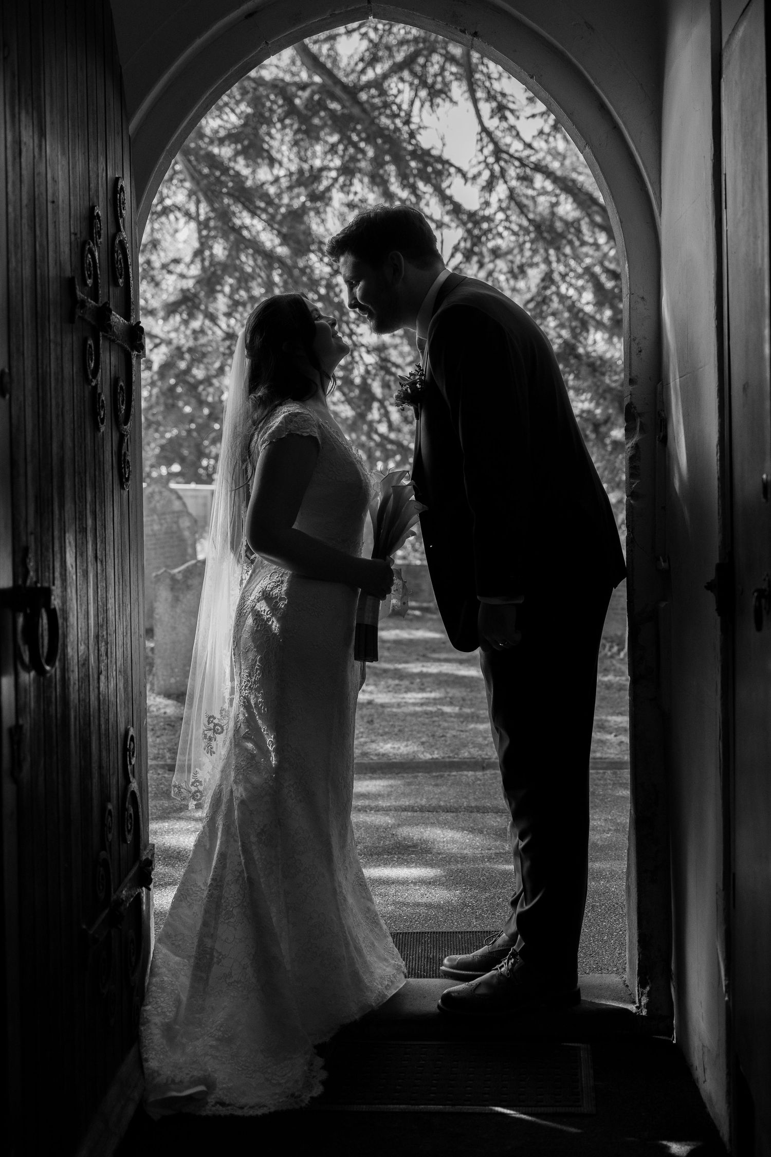 Silhouetted couple in doorway sharing intimate moment on wedding day.