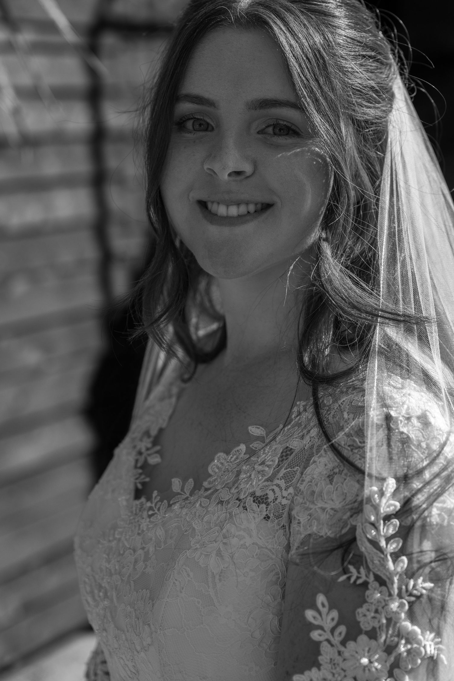 Black and white portrait of bride wearing lace gown and veil.