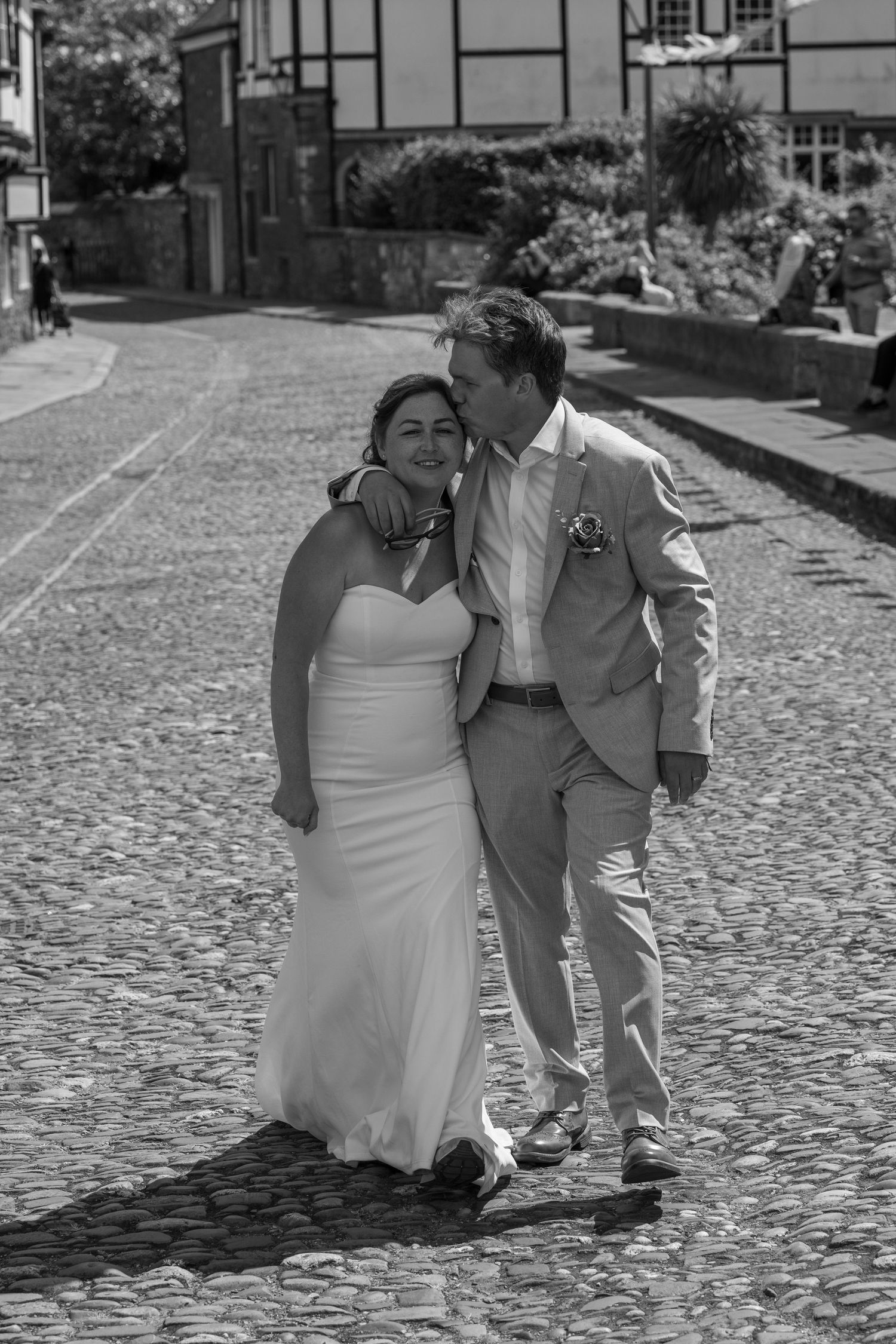 Wedding couple walking together on a cobblestone street in black and white.