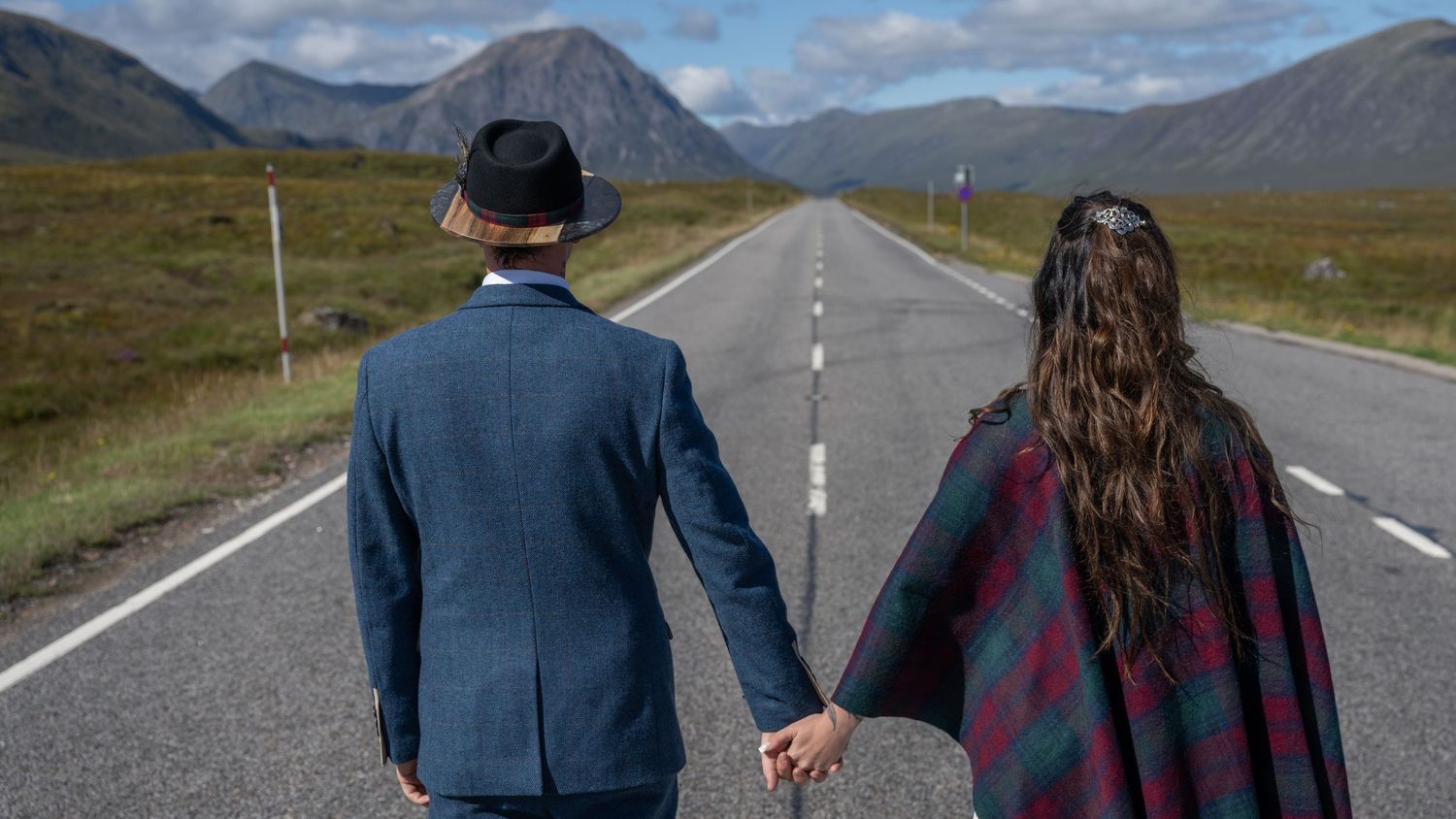 A romantic moment captured from behind on an empty mountain road.