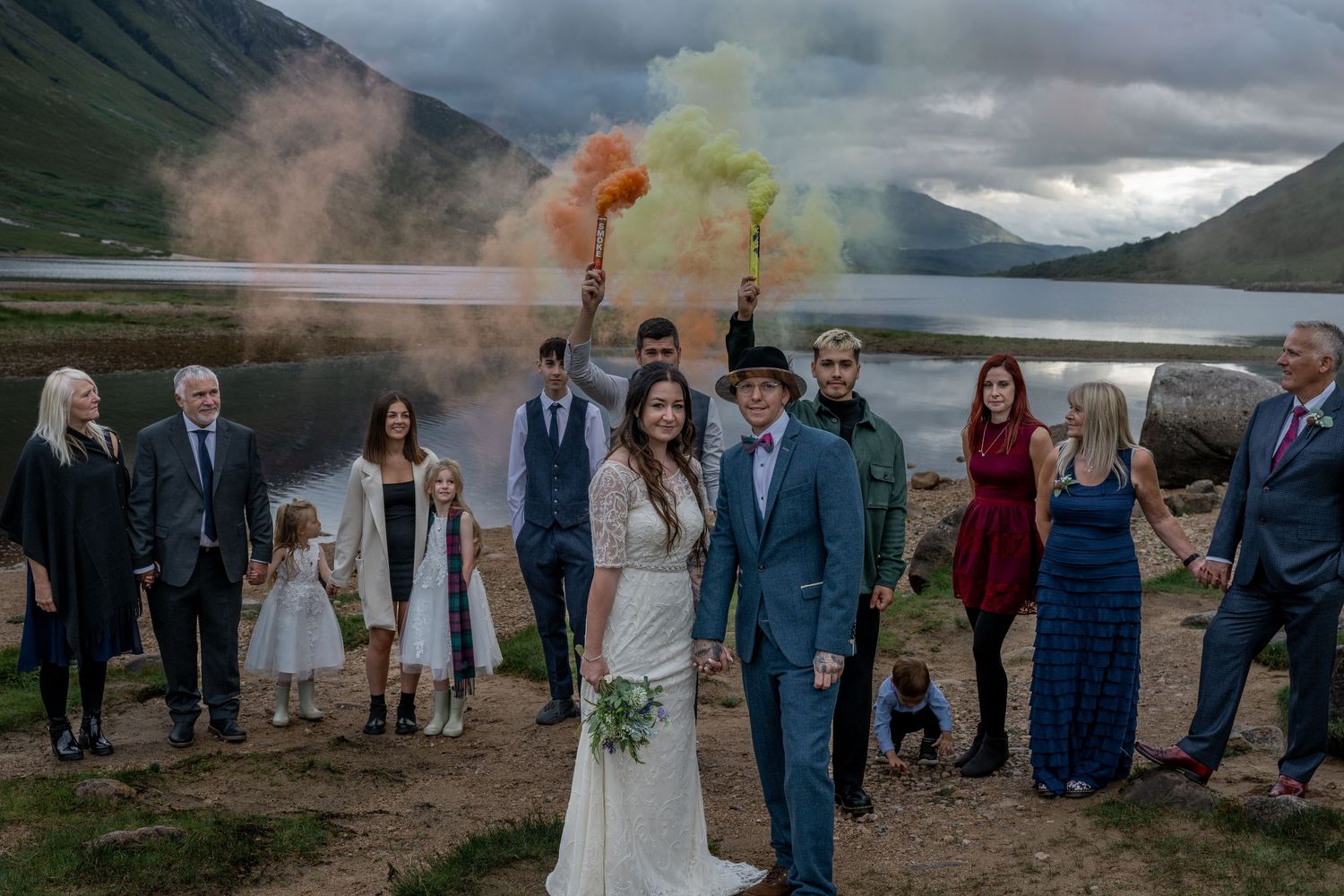 A wedding celebration with colored smoke against a dramatic mountain backdrop.