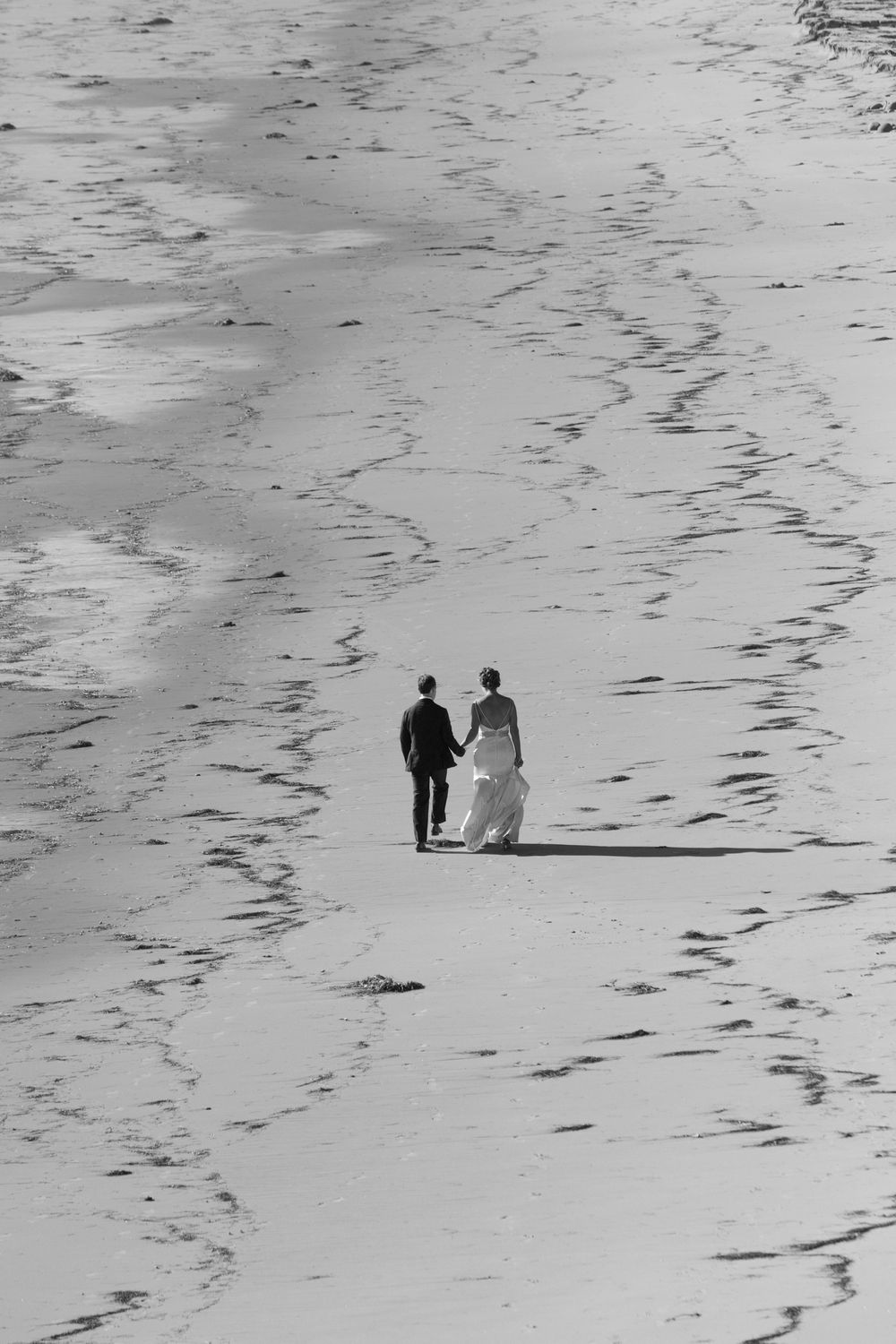 bride and groom holding hands walking down the beach in Santa Barbara