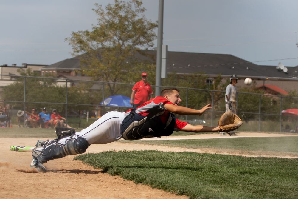 Baseball player makes diving catch attempt during intense game action.