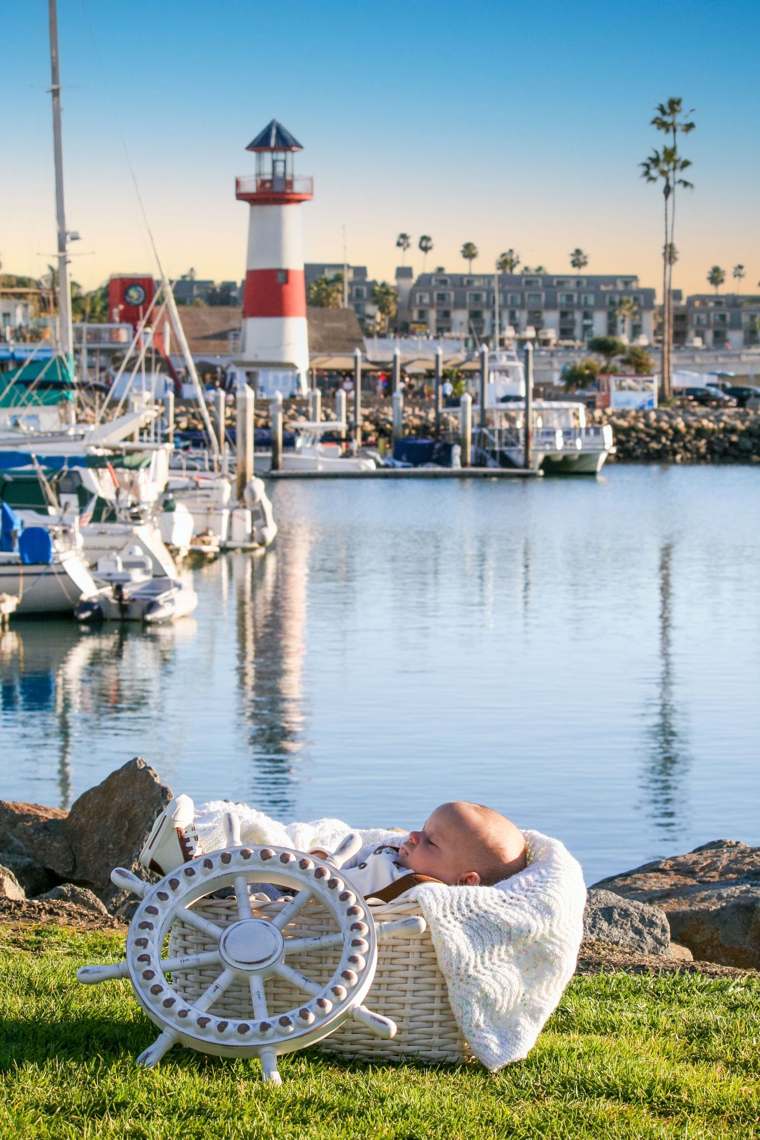 baby in a basket on the grass at the ocean harbor and lighthouse