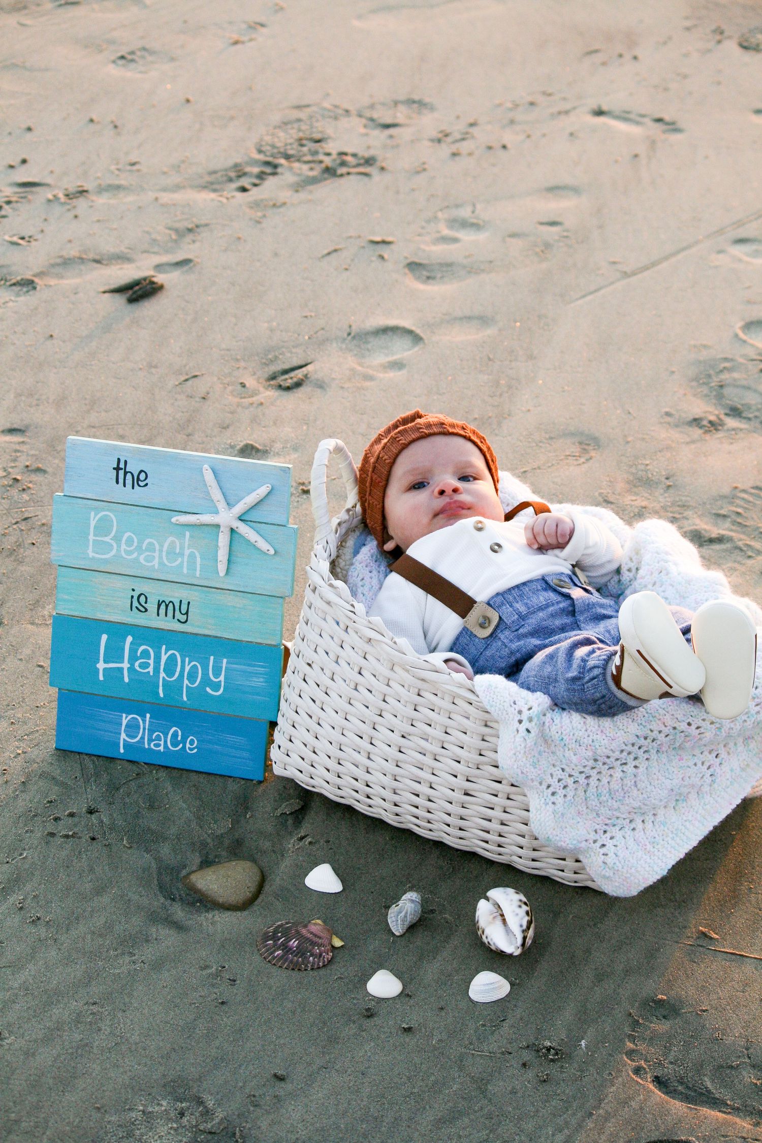 baby in white basket on the sand at the beach