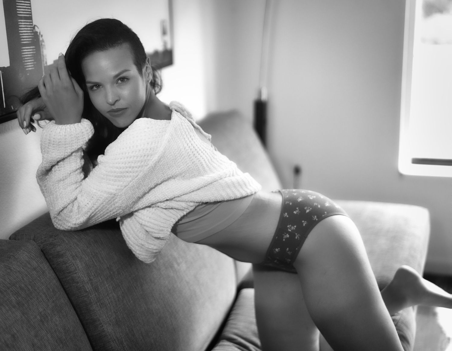 A boudoir photography session featuring intimate poses in a dimly lit living setting.