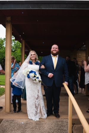 A couple exits their wedding ceremony under a covered walkway.