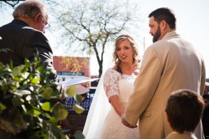 Intimate outdoor wedding ceremony under a tree with guests watching.
