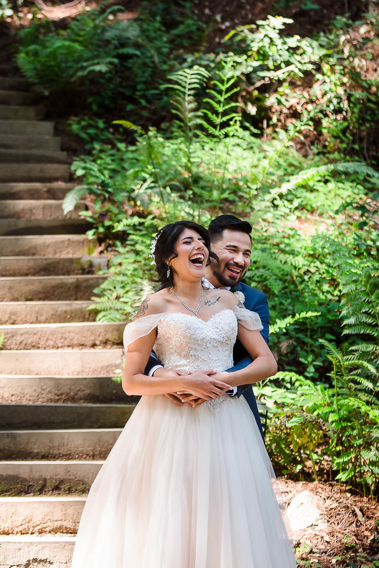 A joyful wedding moment captured on stone steps in a verdant forest setting.