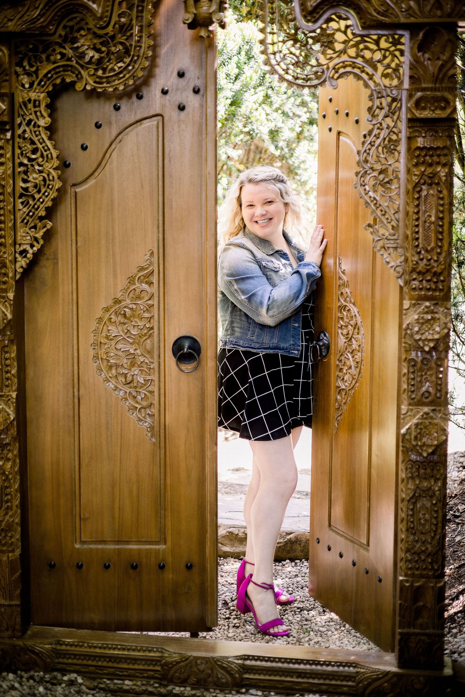 Woman posing in front of ornate wood door in an outdoor garden