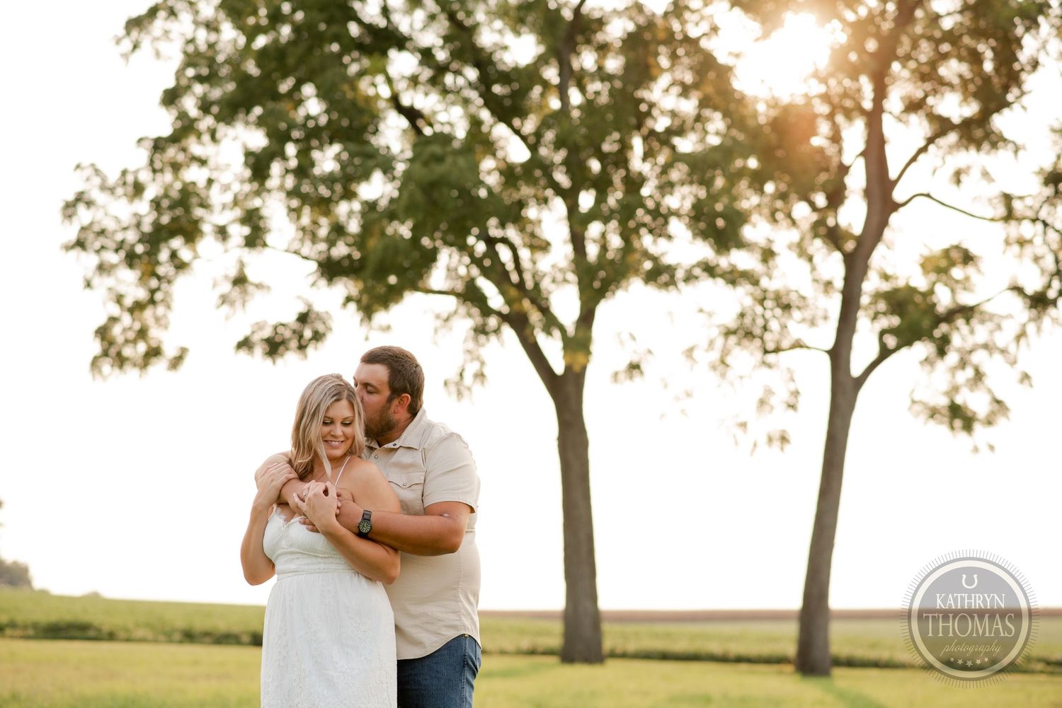 A joyful embrace captured in warm sunset light with trees in the background.