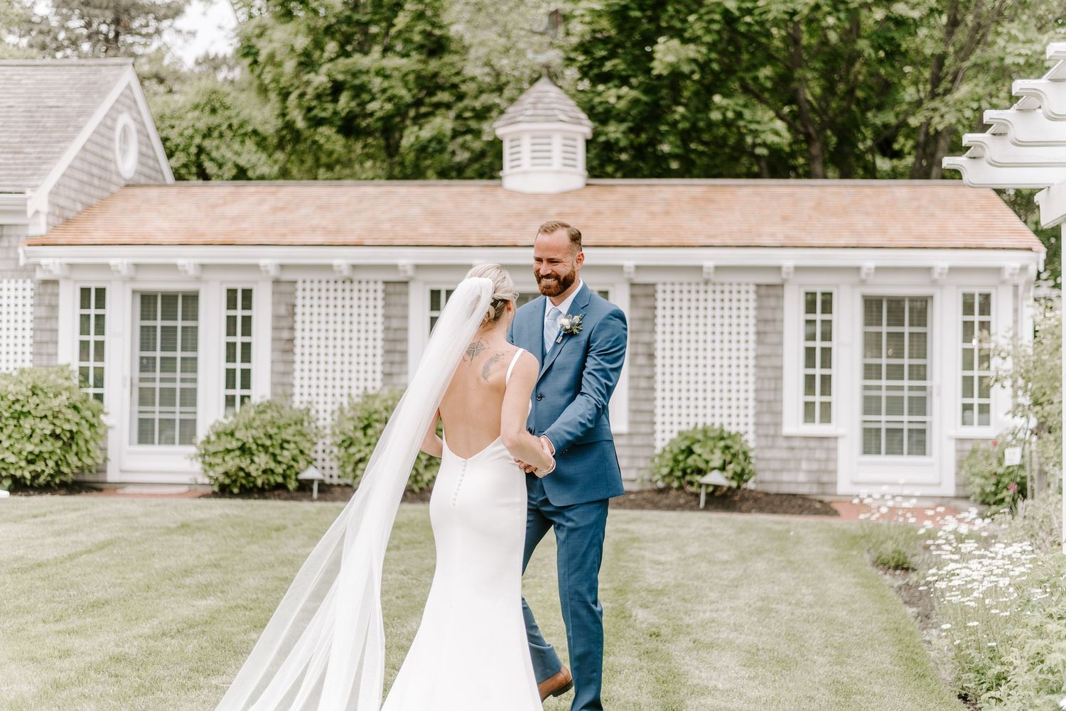 An elegant outdoor scene with a white pergola and classic colonial architecture in the background.