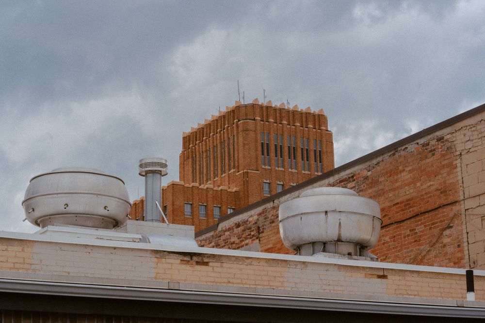 Industrial building rooftop with water tanks against a cloudy sky.