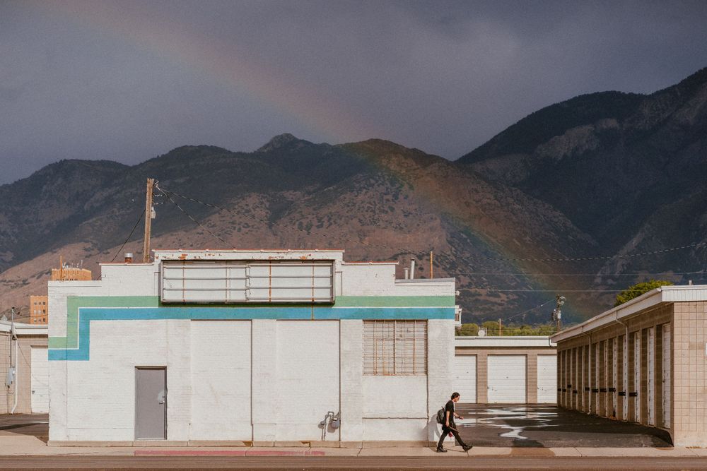White commercial building with a rainbow arching over mountains in the background.