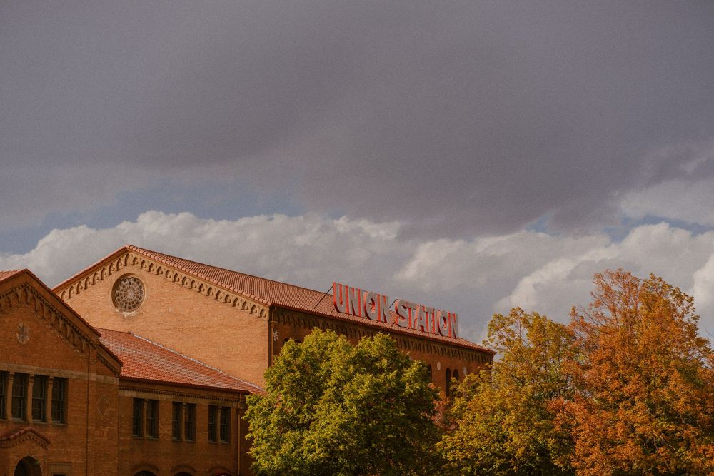 Historic brick building with 'Aloha' sign under dramatic cloudy sky.