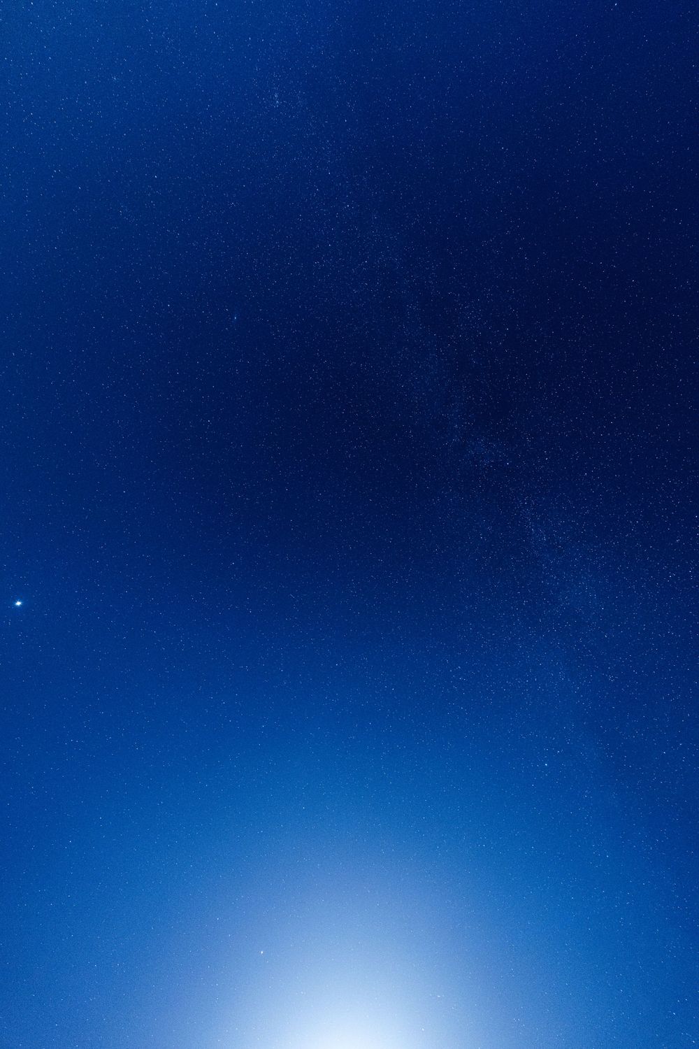 Deep blue night sky with a bright star or planet visible near the horizon.