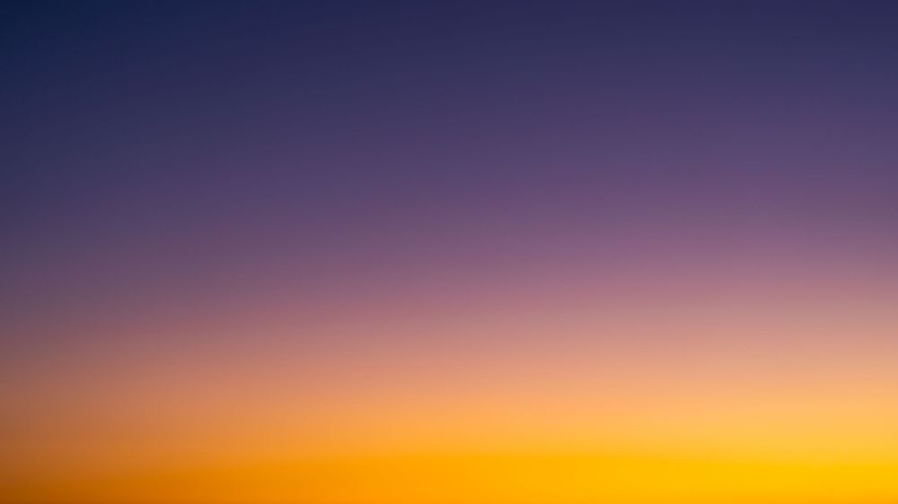 Colorful sunset sky with vibrant orange and purple hues fading into darkness.