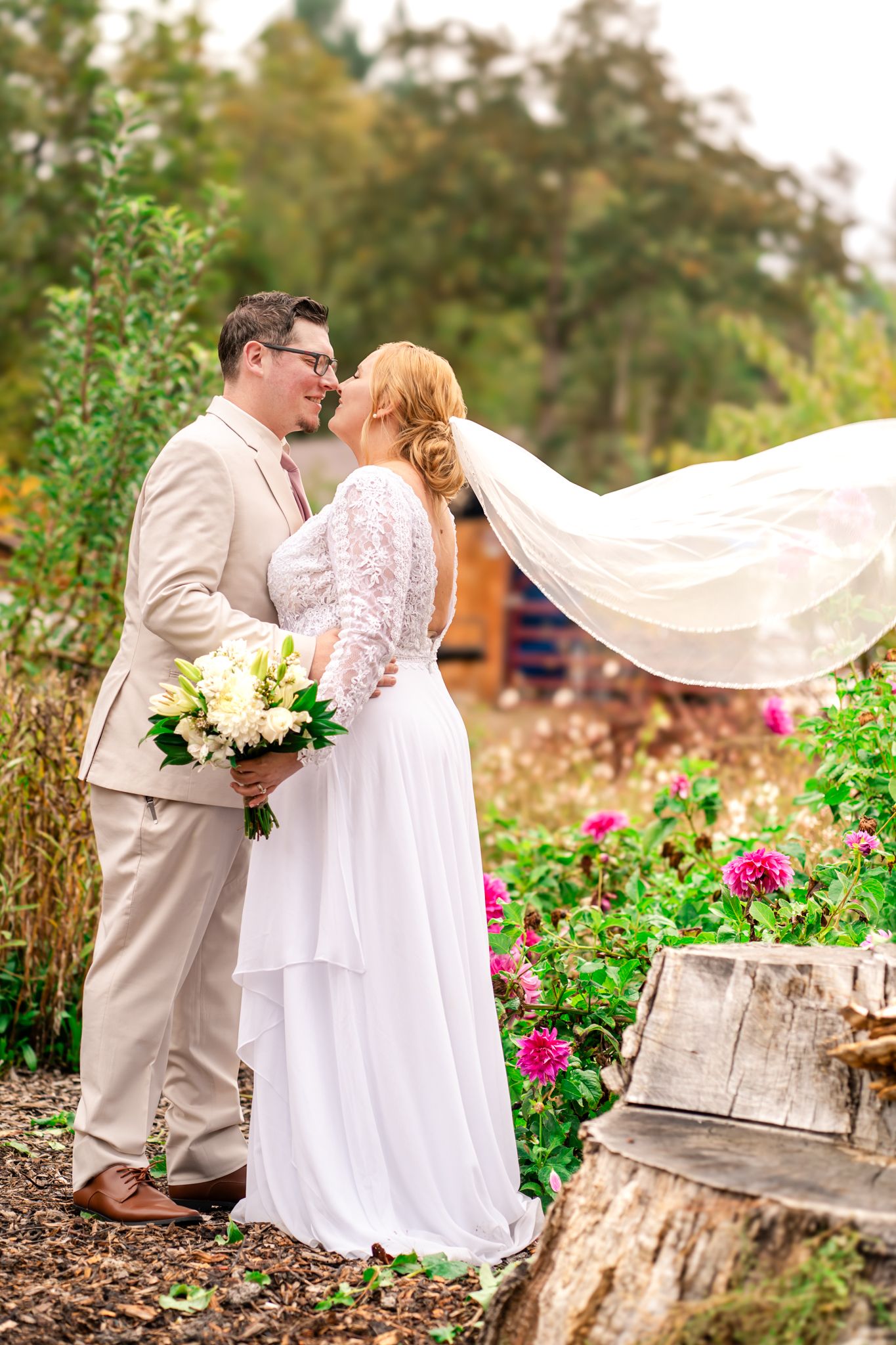 bride and groom share a moment while the veil flies