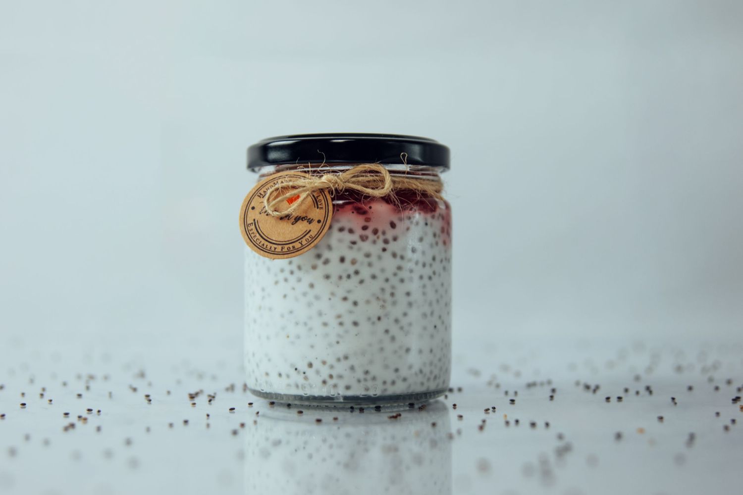 Minimalist white ceramic jar with black lid against light background.