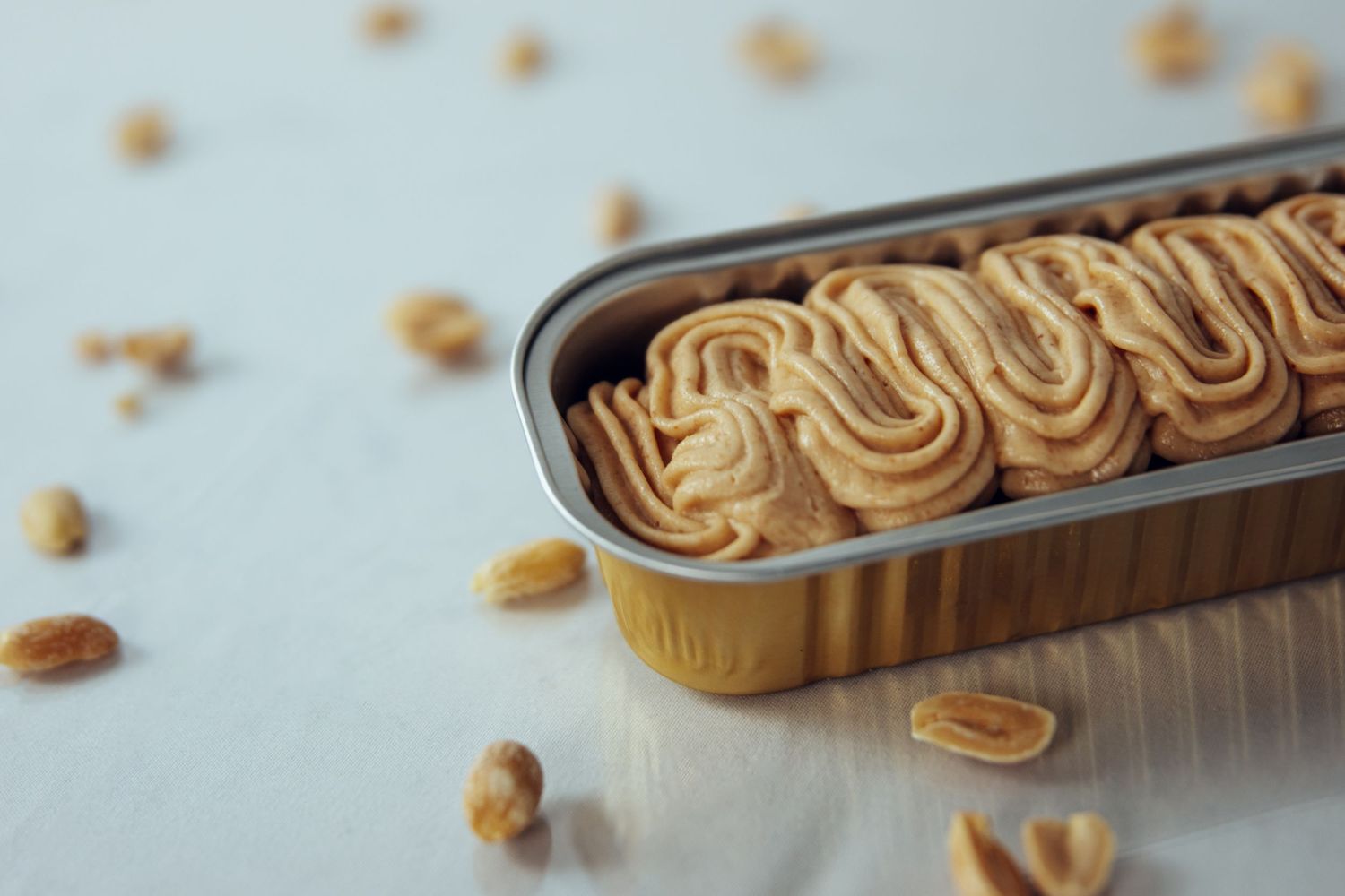 Fresh baked cinnamon rolls arranged in a metal baking pan with scattered nuts.