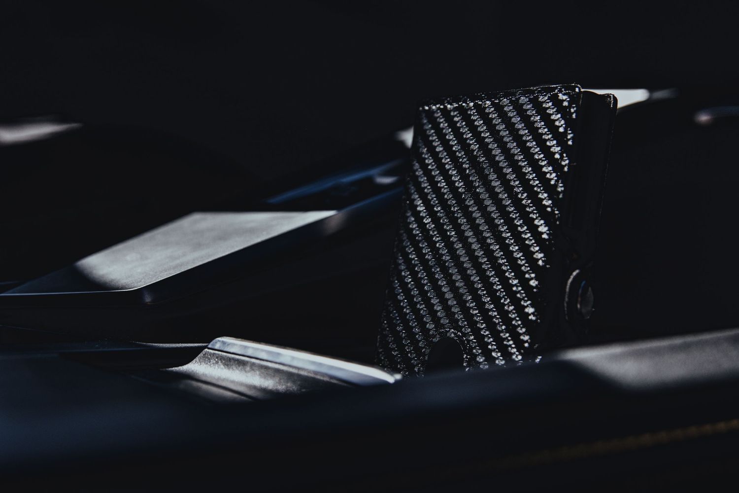 Close-up of a sleek carbon fiber wallet or card holder against dark background.