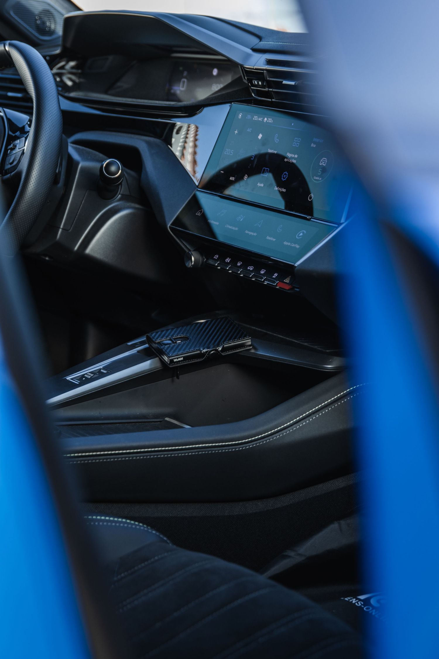 Modern car interior showing digital dashboard display and steering wheel in blue lighting.