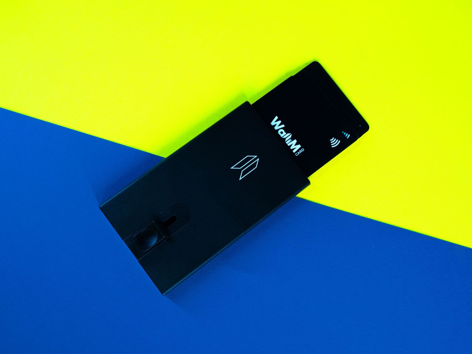 Black wallet lying on split yellow and blue background.
