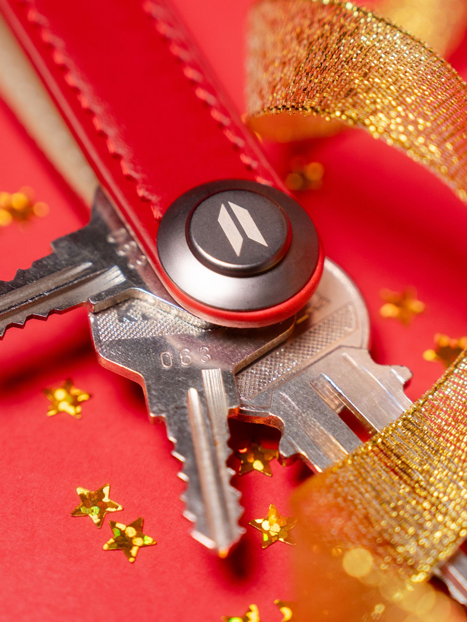 Keys with a branded logo against a red background with gold ribbon and star decorations.