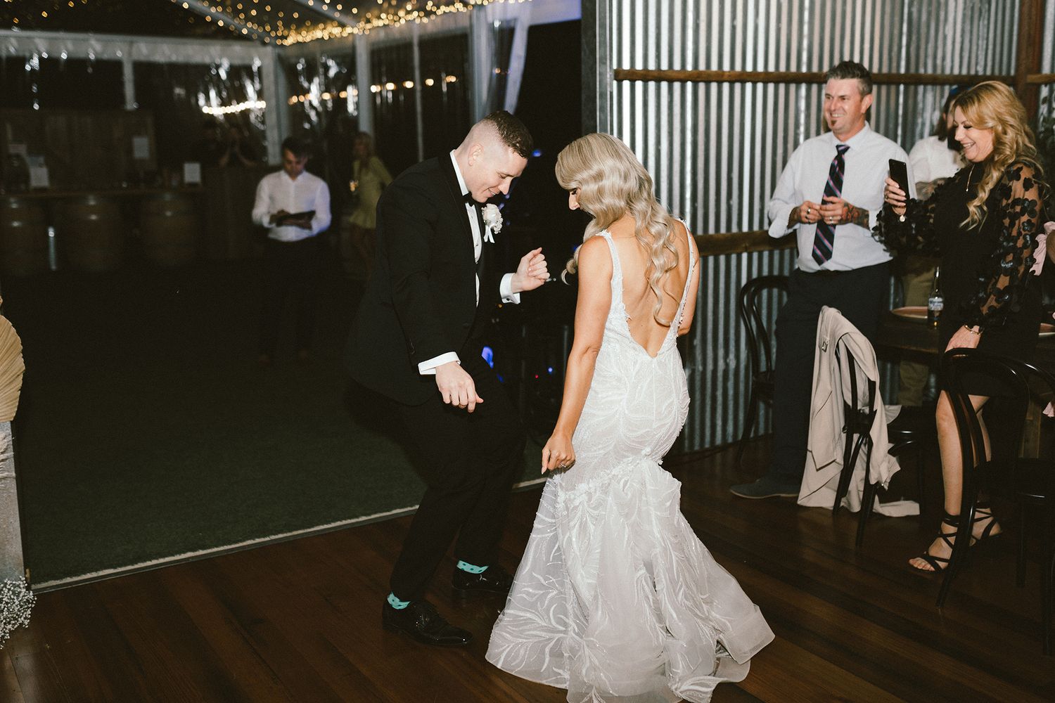 Wedding party dancing and celebrating in a dimly lit industrial venue.