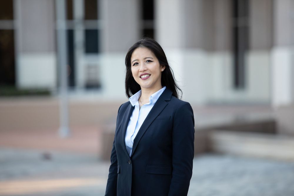 Professional woman in navy blazer smiling outdoors, ideal for business or corporate headshot photography.