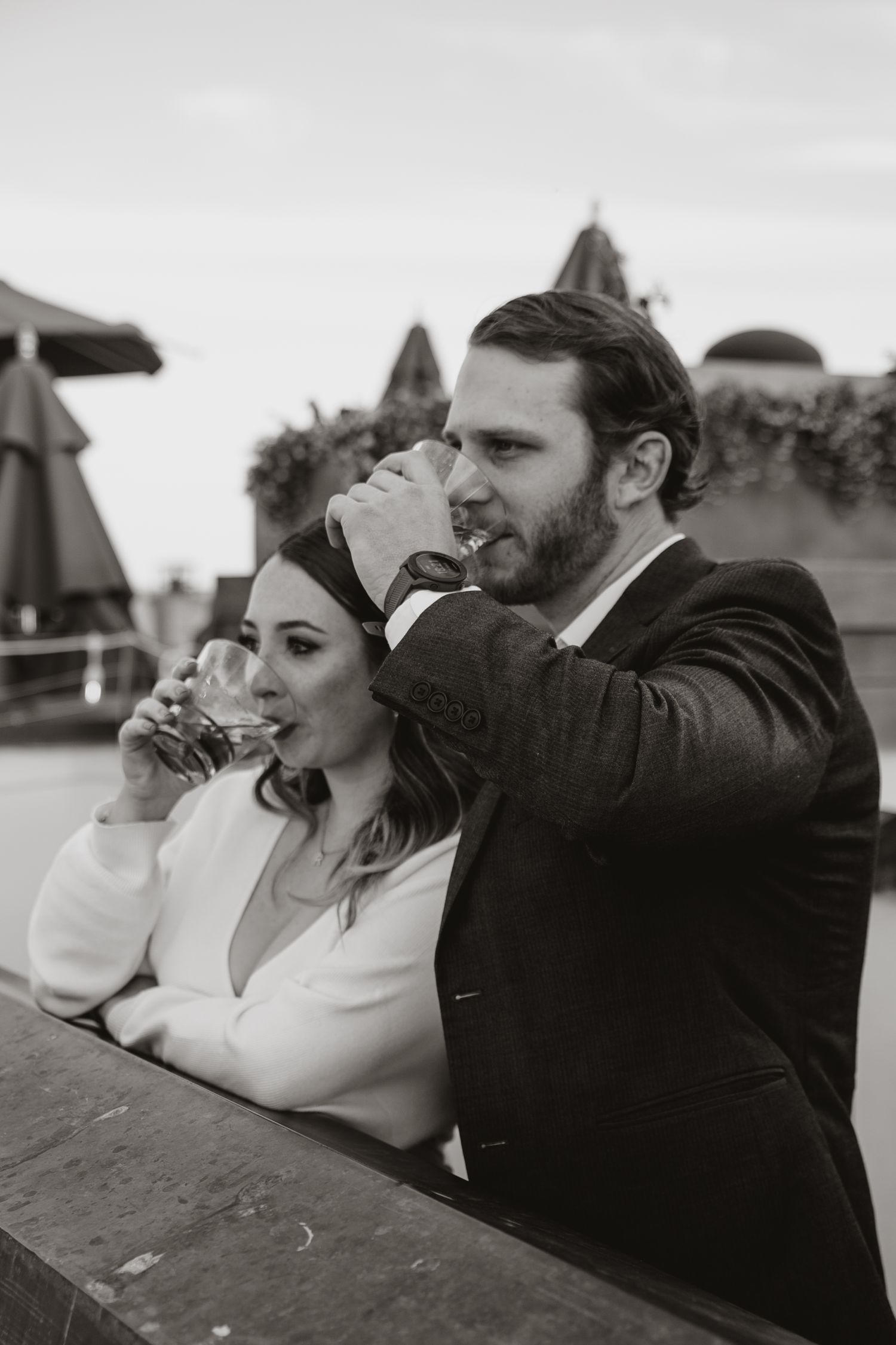 A man and a woman both take a drink while looking off into the distance
