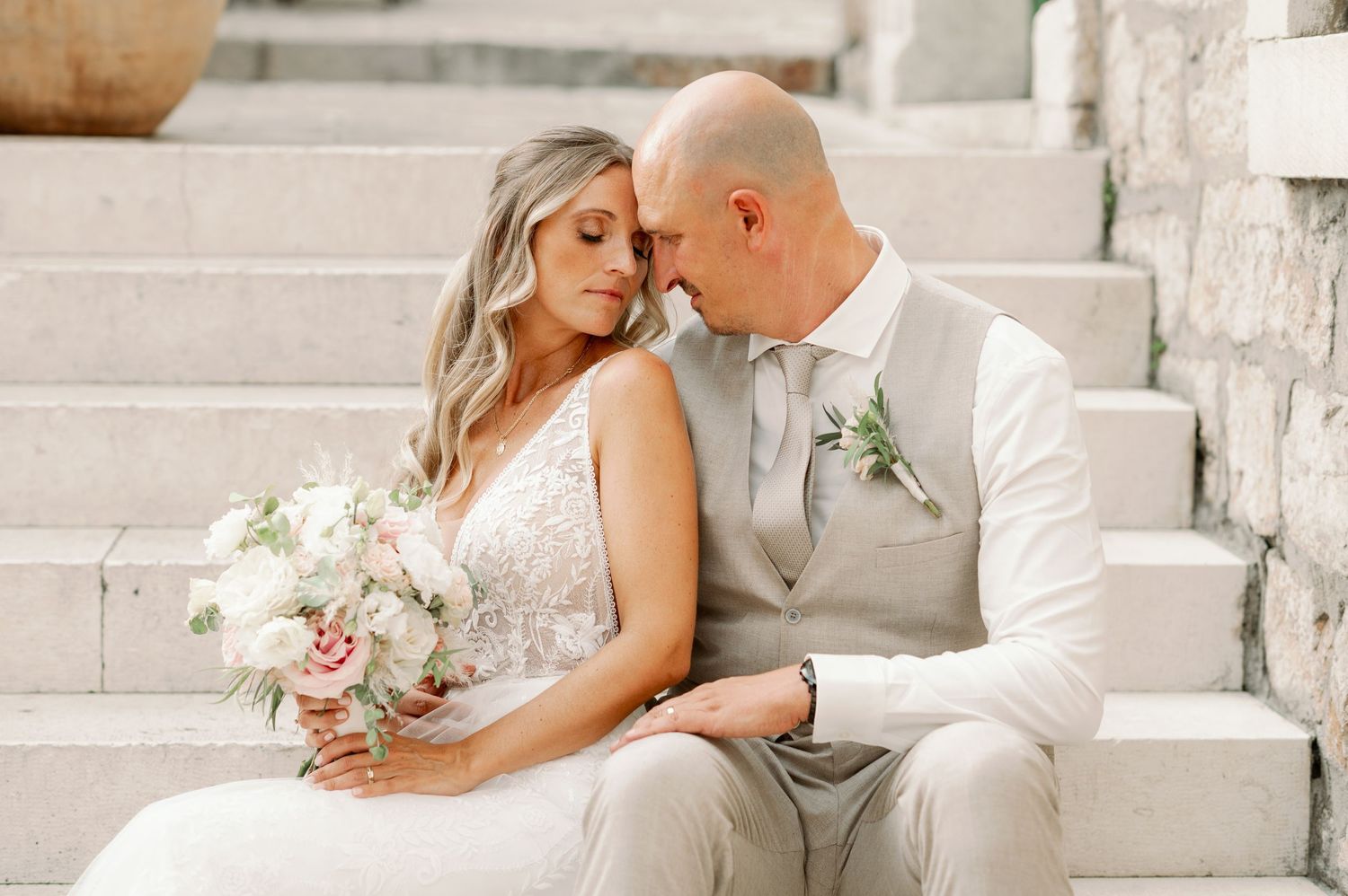 Intimate wedding portrait on stone steps with soft pink and white bouquet.