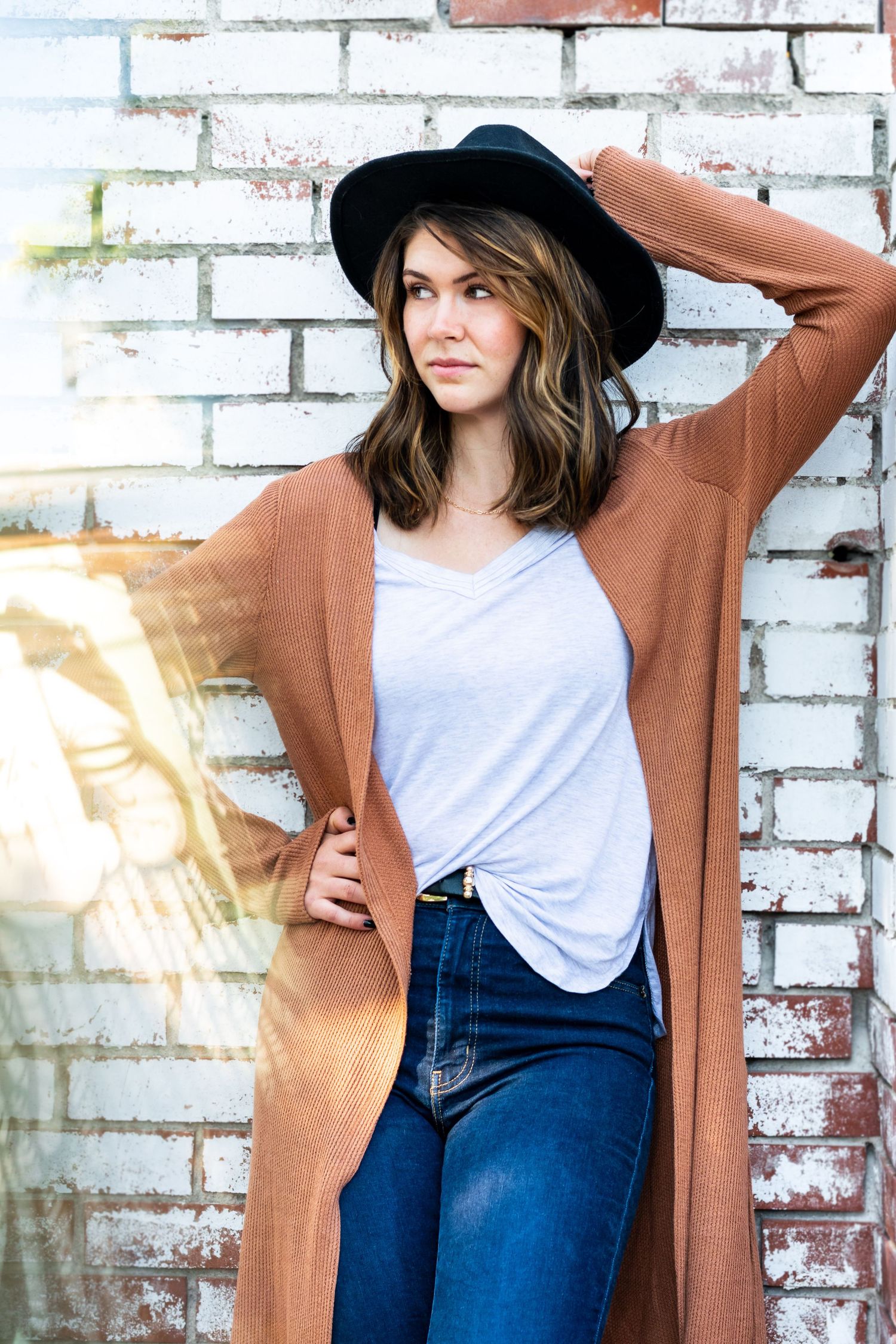 Woman with hat standing up against white brick located in the River North District of Denver, Colorado