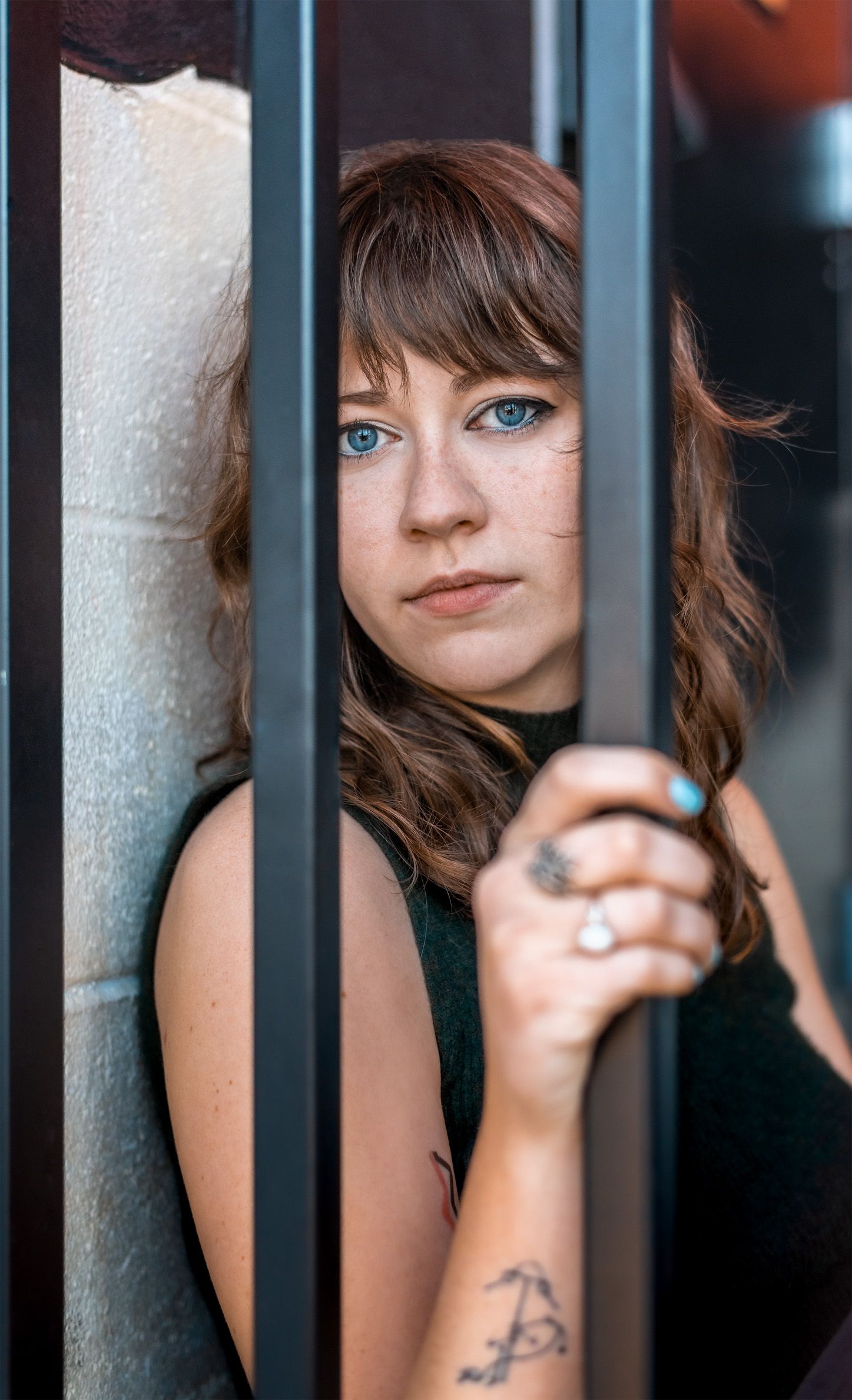 Portrait of woman with brown hair and blue eyes looking through railing in the River North District of Denver, Colorado