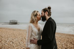 close up of a couple kissing on the beach in Brighton wearing wedding clothing