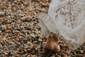 close up of the wind blowing a wedding dress up to reveal a cowboy boot on Brighton Beach
