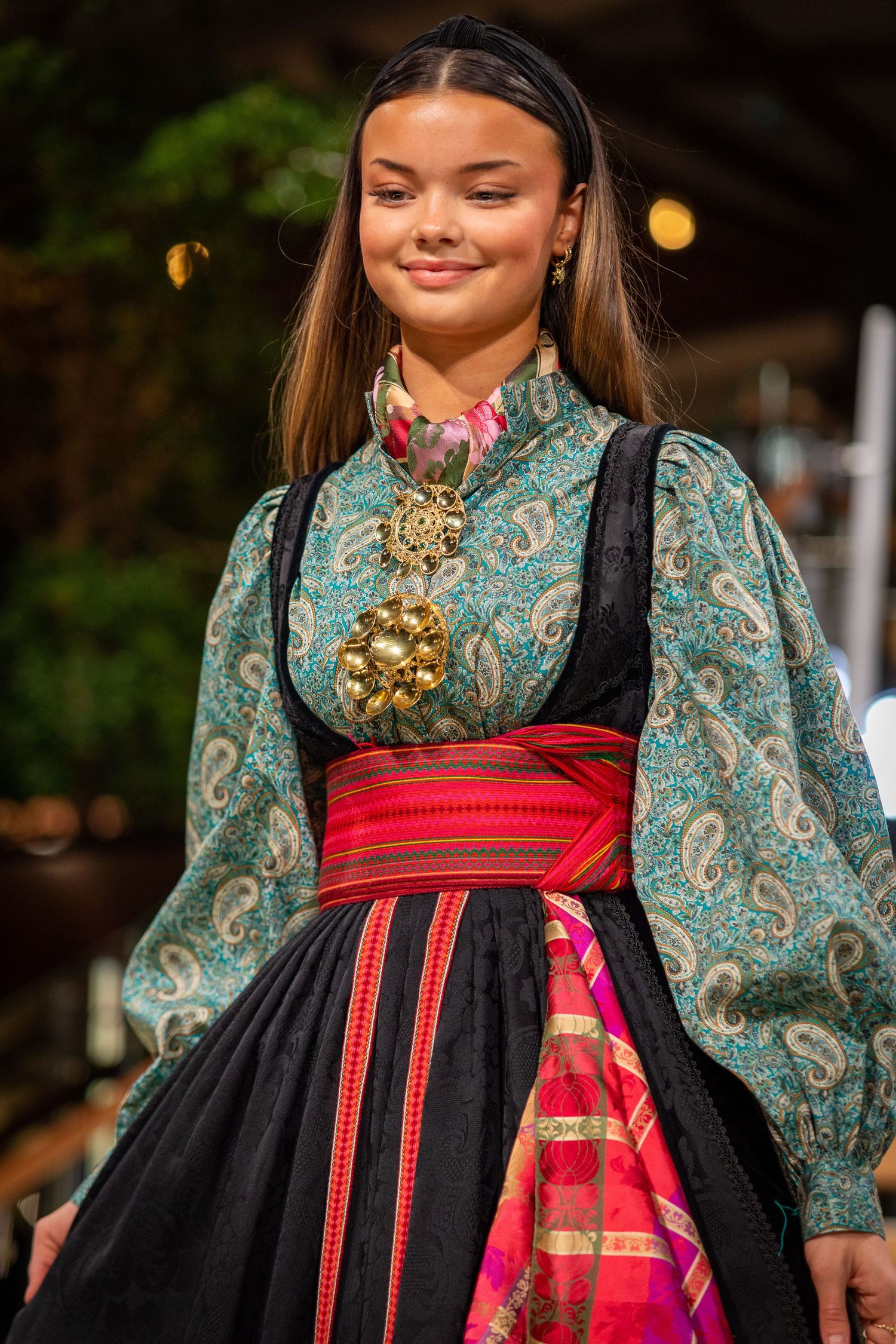 Young woman in traditional Norwegian bunad folk costume with gold brooch.