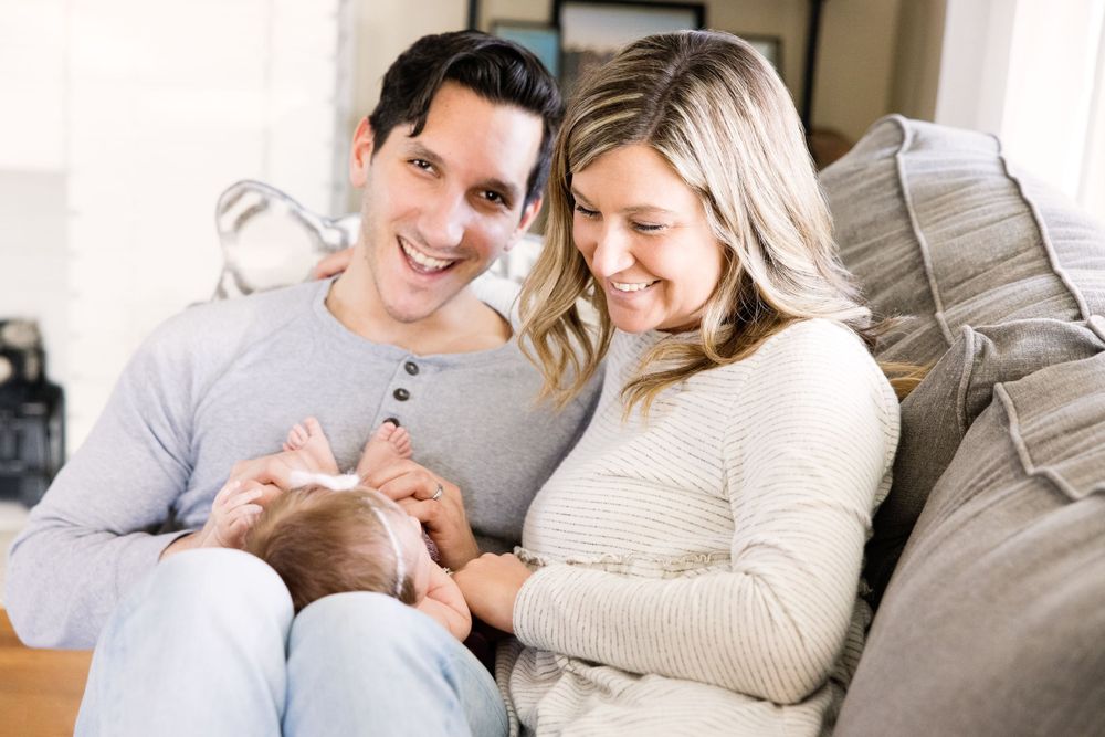 baby girl lifestyle photography of young couple on couch playing with newborn