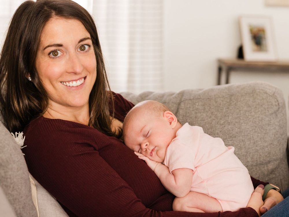 Newborn Lifestyle photography of mother and infant girl snuggle on couch