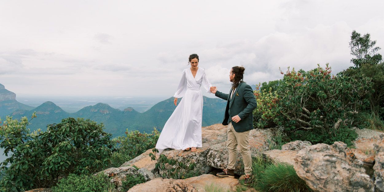 Groom helps bride down a rock, Blyde River Canyon
