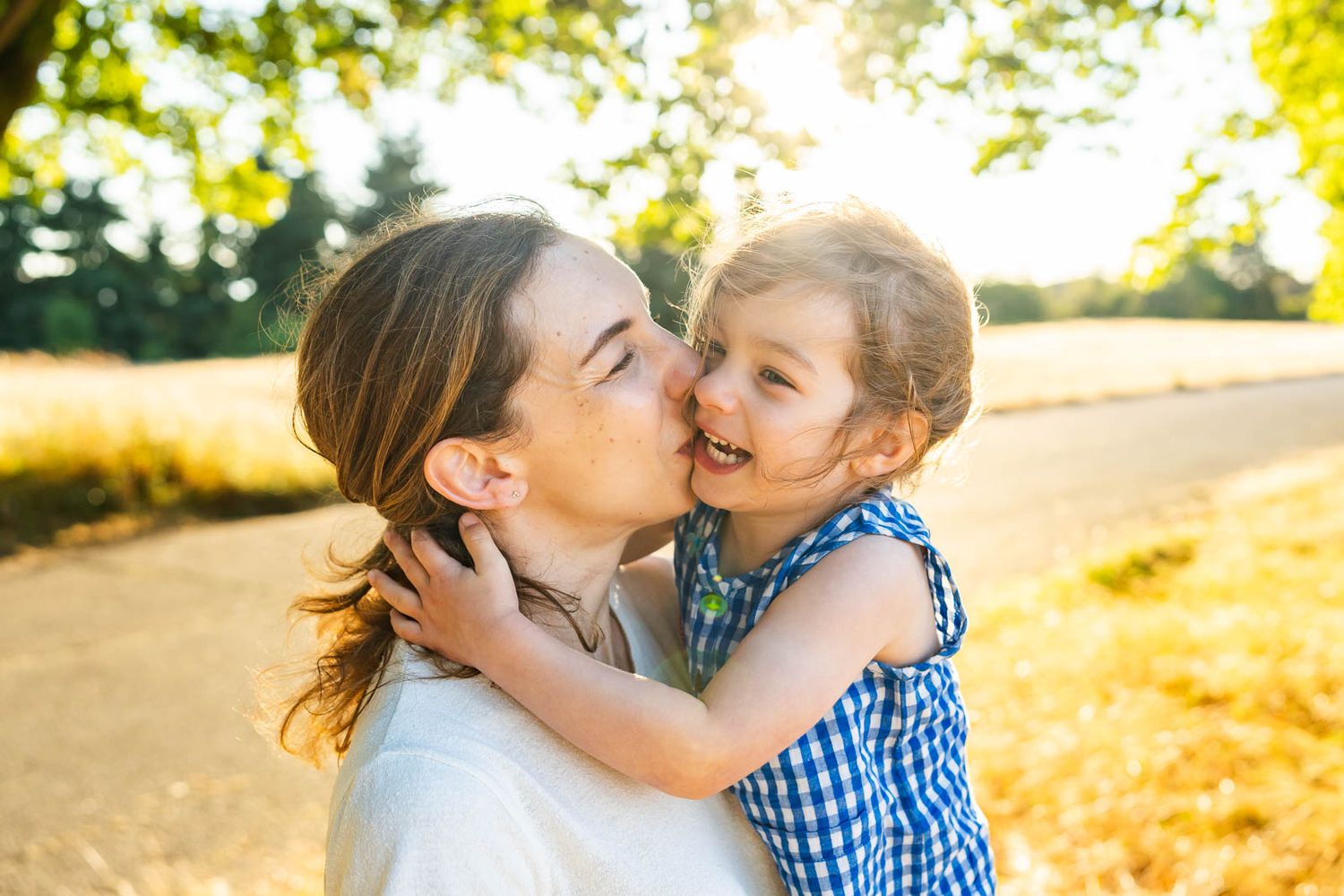 Mother kissing daughter at Discovery Park at sunset.