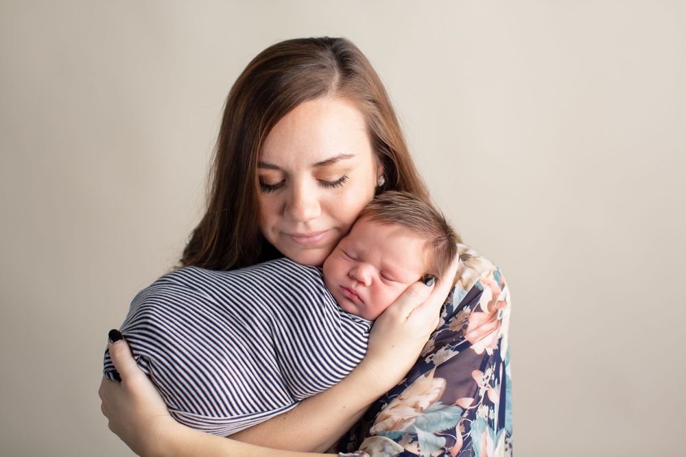 Tender moment between parent and sleeping baby in striped outfit.