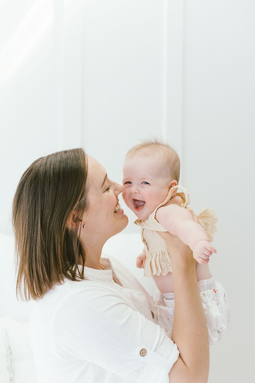 Joyful interaction between parent and baby against white background captures pure happiness.
