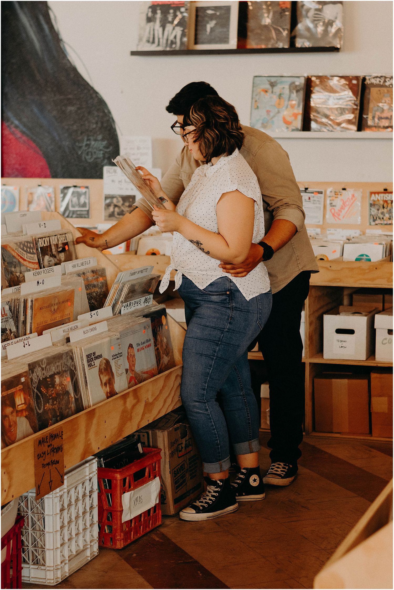 A couple searches through vinyl records together in a cozy record shop setting.